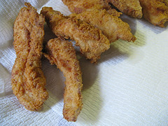 Fried chicken strips draining on paper towel