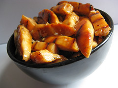 Mandarin chicken pieces in black bowl