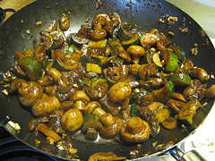 Mushrooms and zucchini cooking in wok