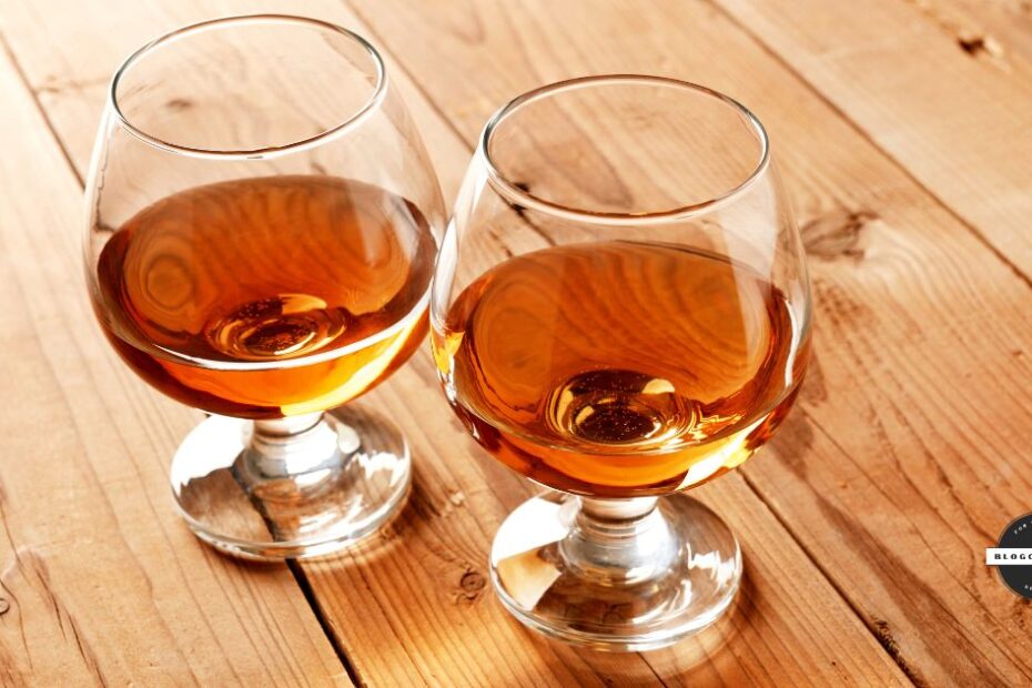 Two glasses of brandy on wooden surface